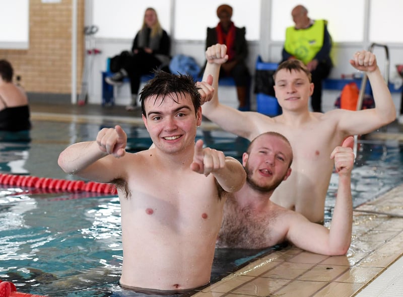 Three male swimmers, learners at MK SNAP, are in the water of a swimming pool and giving a 'thumbs up'